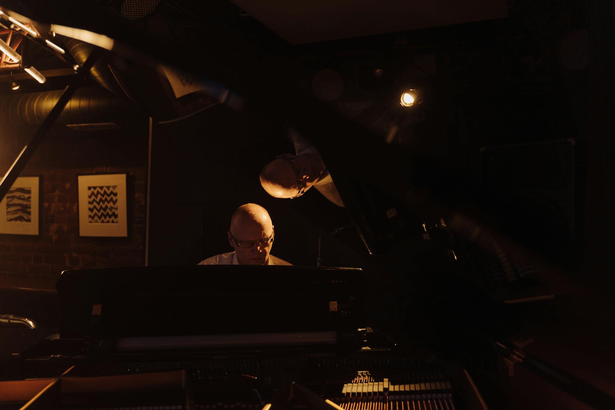 An elderly man playing piano in a dark jazz club setting, captured in a moody atmosphere.