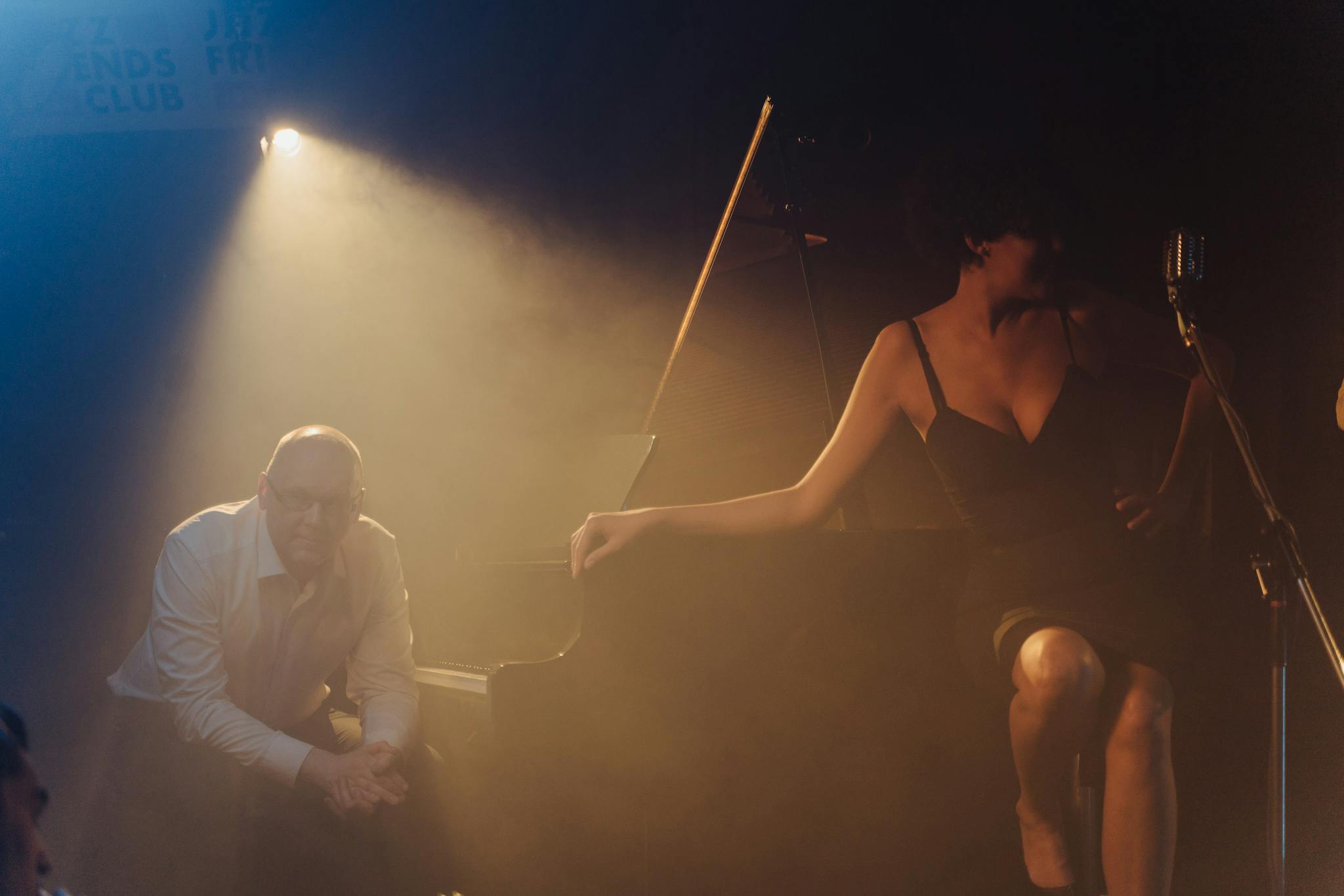 Moody jazz club performance featuring a pianist and singer on stage.