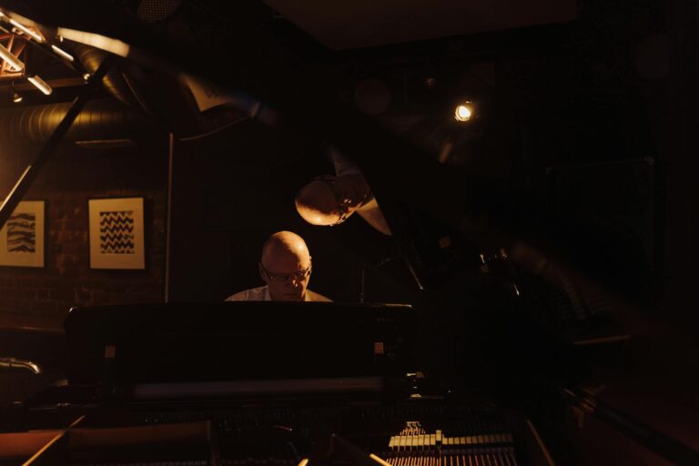 An elderly man playing piano in a dark jazz club setting, captured in a moody atmosphere.